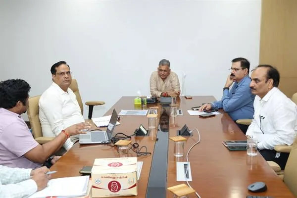 कॉन्फ्रेंस टेबल पर अधिकारी लैपटॉप और फाइलों के साथ बैठे हैं, सामने आयुष प्रतीक वाली पेटी